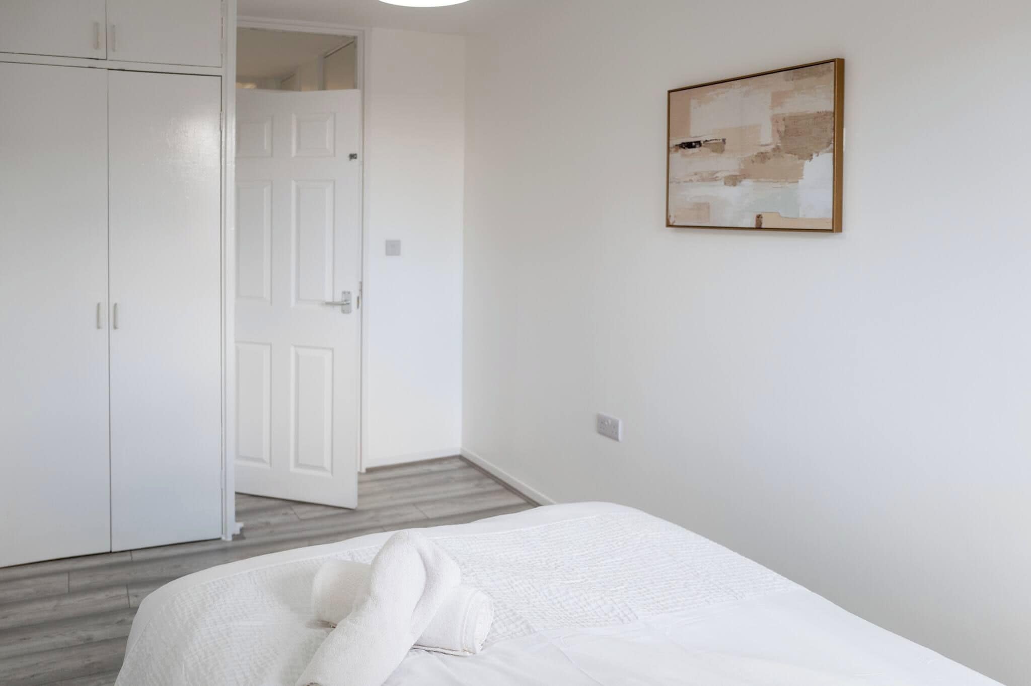 A bedroom with a bed, a wardrobe, and a door leading to another room.