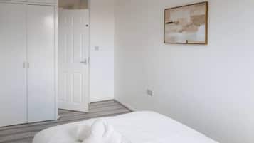 A bedroom with a bed, a wardrobe, and a door leading to another room.
