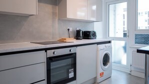 Una cucina moderna con forno integrato, lavatrice e macchina da caffè sul piano di lavoro.