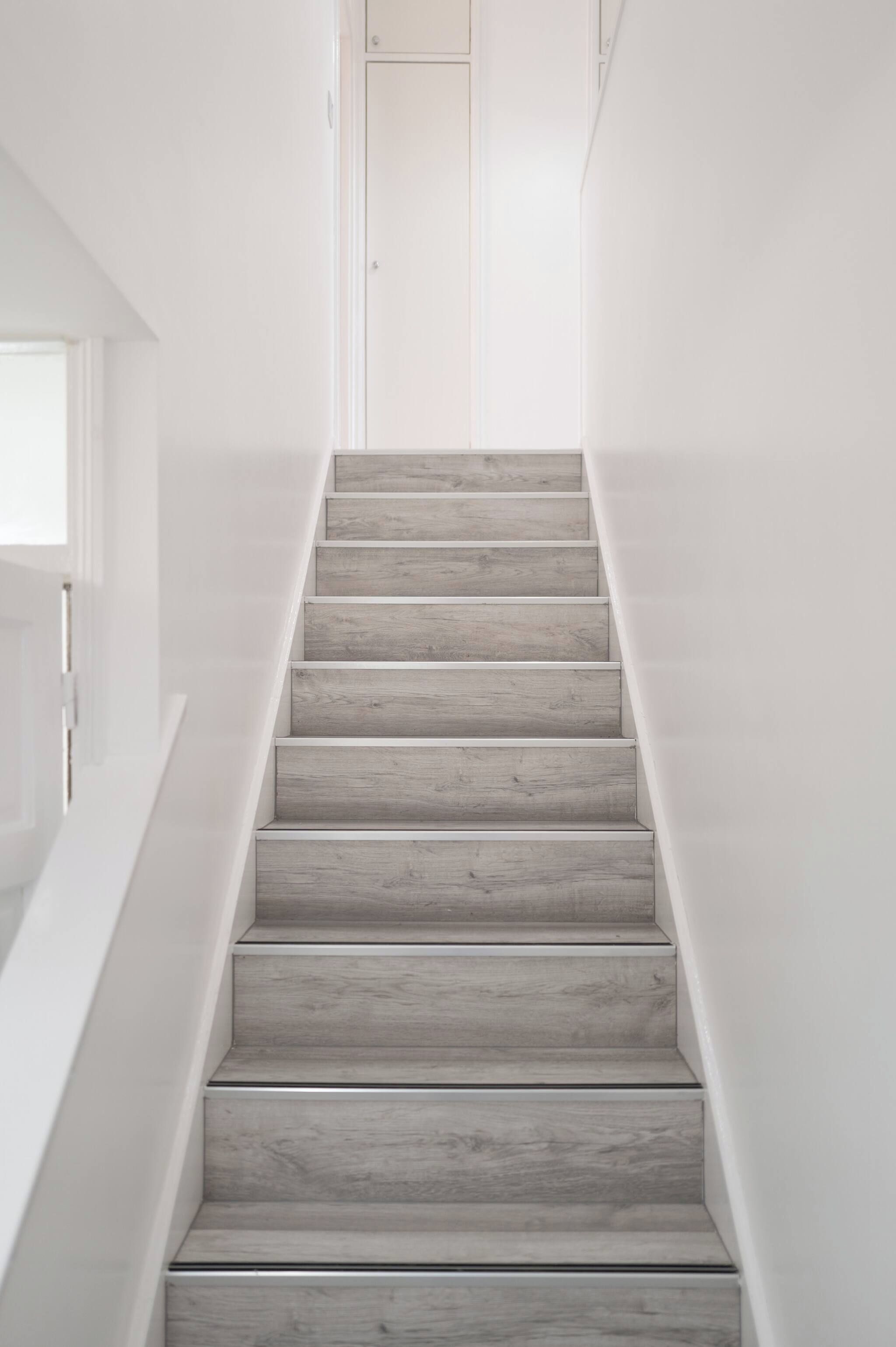 A staircase with wooden steps and white walls.