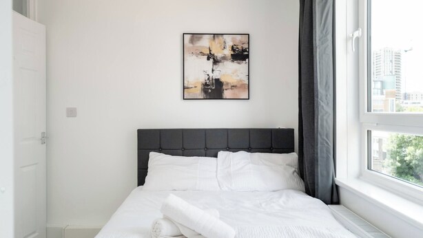 Una camera da letto moderna con un letto, un quadro e una finestra con tende.