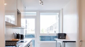 Una cucina moderna con forno integrato, macchina del caffè e forno a microonde su un piano di lavoro.