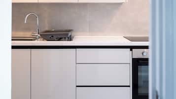 A modern kitchen with white cabinetry, a built-in oven, and a stainless steel sink.