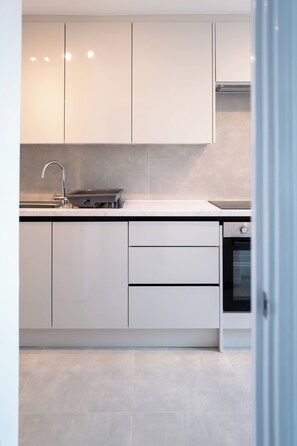 Eine moderne Küche mit weißen Schränken, einem eingebauten Backofen und einer Edelstahl-Spüle.