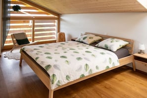 Un dormitorio con una cama de madera, una mesita de noche, una silla y una ventana con persianas.