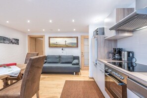A modern kitchen with a built-in oven and a dining area with a wooden table and chairs. - Holiday apartment in Maishofen with sauna (Maishofen)