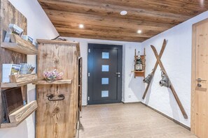 Interior de fusta amb una porta, prestatges amb revistes i esquís a la paret.