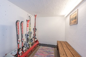 A ski storage area with skis and poles, a wooden bench, and a textured wall. - Holiday apartment in Maishofen with sauna (Maishofen)