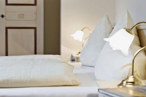 Une chambre d’hôtel avec un lit, des oreillers, une table de chevet et une lampe.