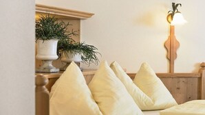 A bed with a wooden headboard, multiple pillows, a bedside table with a potted plant, and a wall-mounted lamp. - Apartment in Dorfgastein with swimming pool (Dorfgastein)