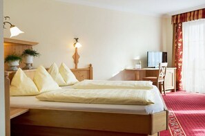A hotel room with a double bed, bedside tables, a desk with a chair, a television, and a red carpet. - Apartment in Dorfgastein with swimming pool (Dorfgastein)