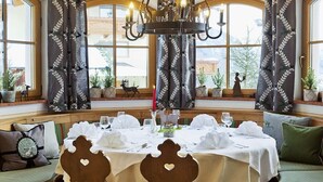 A dining area with a round table set for a meal, large windows, and a chandelier. - Apartment in Dorfgastein with swimming pool (Dorfgastein)