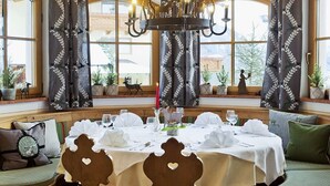 Een eetgedeelte met een ronde tafel gedekt voor een maaltijd, grote ramen en een kroonluchter.