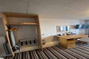 Ein Hotelzimmer mit einem Etagenbett, einem Schreibtisch, einem Stuhl, einem Flachbildfernseher und einem Streifenmuster-Teppich.