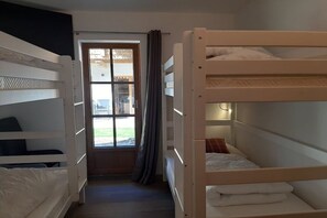 A room with bunk beds, a window with curtains, and a door leading outside. - Hochalmbahnen Chalet (Rauris)