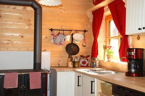 A kitchen with a wood stove, hanging pots, and a coffee maker. - Holiday home in Gosau with swimming pool (Gosau)