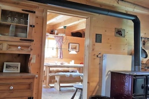 A wooden interior with a dining area, a stove, and a cabinet with glassware. - Holiday home in Gosau with swimming pool (Gosau)