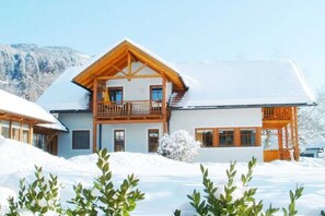 A two-story chalet with a balcony, surrounded by snow. - Holiday apartment with 1 bedroom (Seeboden)