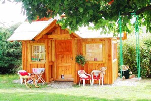 Een houten blokhut met een veranda, schommelstoelen en een schommel.