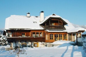 Een houten chalet met een balkon, omgeven door sneeuw.