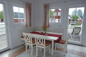 A dining area with a white table and chairs, a red tablecloth, and a vase with flowers. - House Scharmützelsee (Wendisch Rietz)