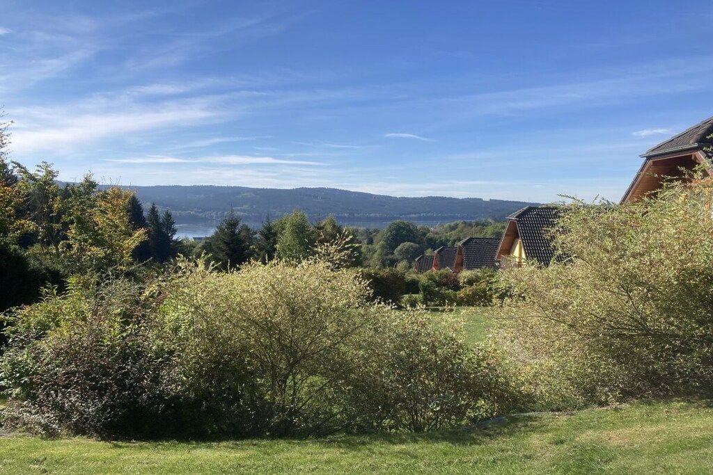 Un quartier résidentiel où se trouve une maison dotée d’un toit en pente, entourée d’une végétation luxuriante et offrant une vue sur des collines lointaines.