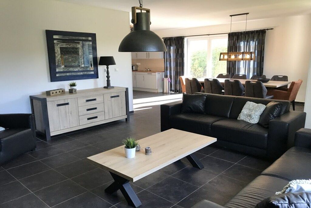 Un salon moderne comprenant un canapé, une table basse et un coin repas avec des chaises et une table.