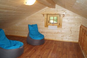 Een houten hutje met twee zakenzakken, een klein raam en een houten plafond.