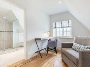 A modern, well-lit room with a glass shower, a desk with a chair, and a sofa. - Holiday Home Pidder Hus Kampen / Sylt (Kampen)