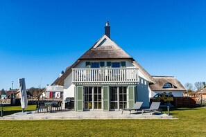 Ein Haus mit einem steilen Satteldach, einem Balkon mit weißen Geländern und einem großen Eingang mit Glastür.