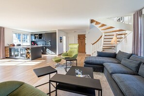 A modern living space with a kitchen, a staircase, and seating areas. - Holiday home with 1 bedroom (18445 Kramerhof, Deutschland)