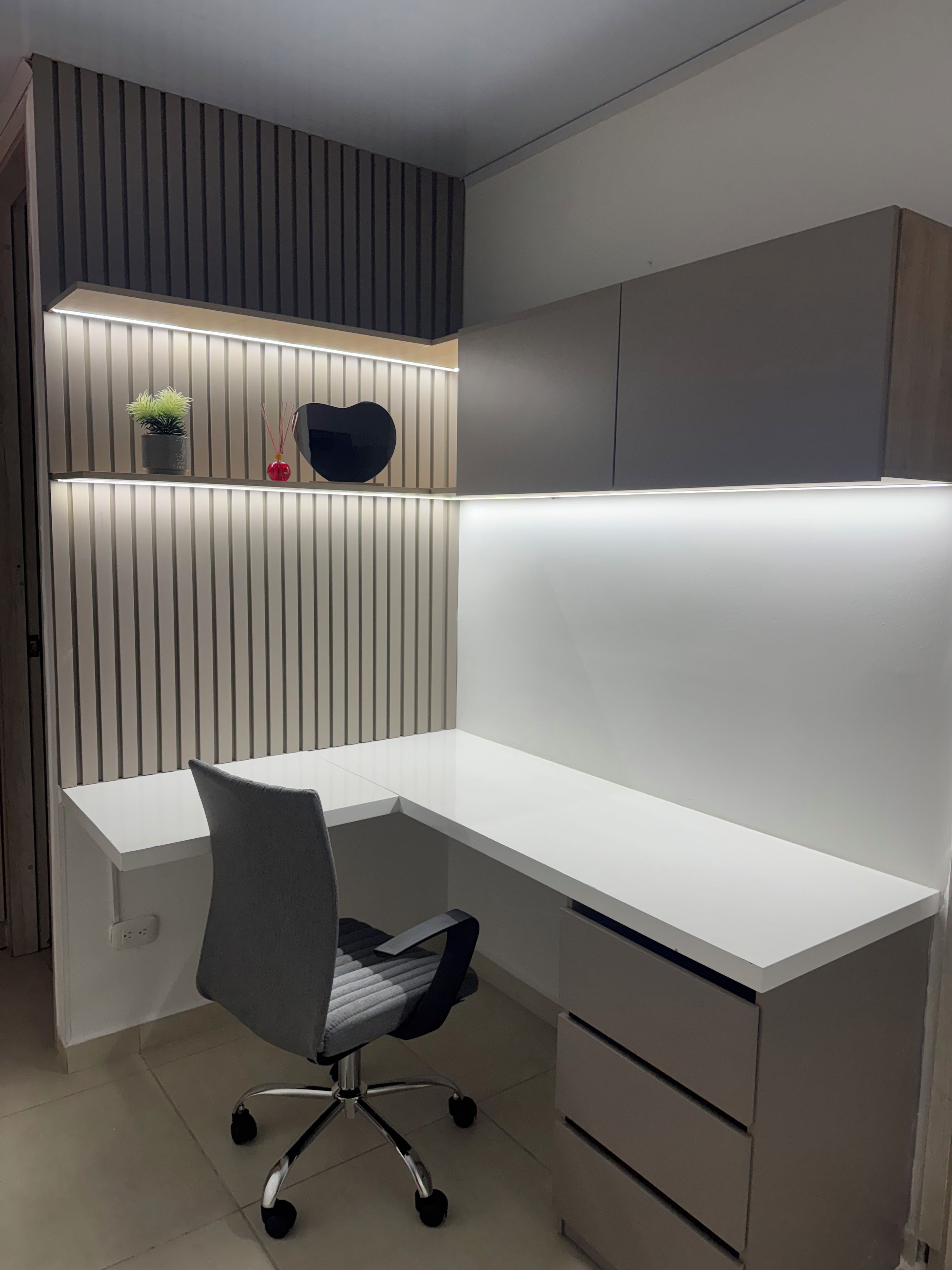 Un bureau moderne, avec une chaise, une plante en pot et un objet décoratif posé sur une étagère.