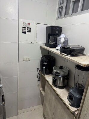 Une cuisine équipée d’une machine à café, d’un mixeur, d’une mijoteuse et d’une bouilloire posée sur le plan de travail.