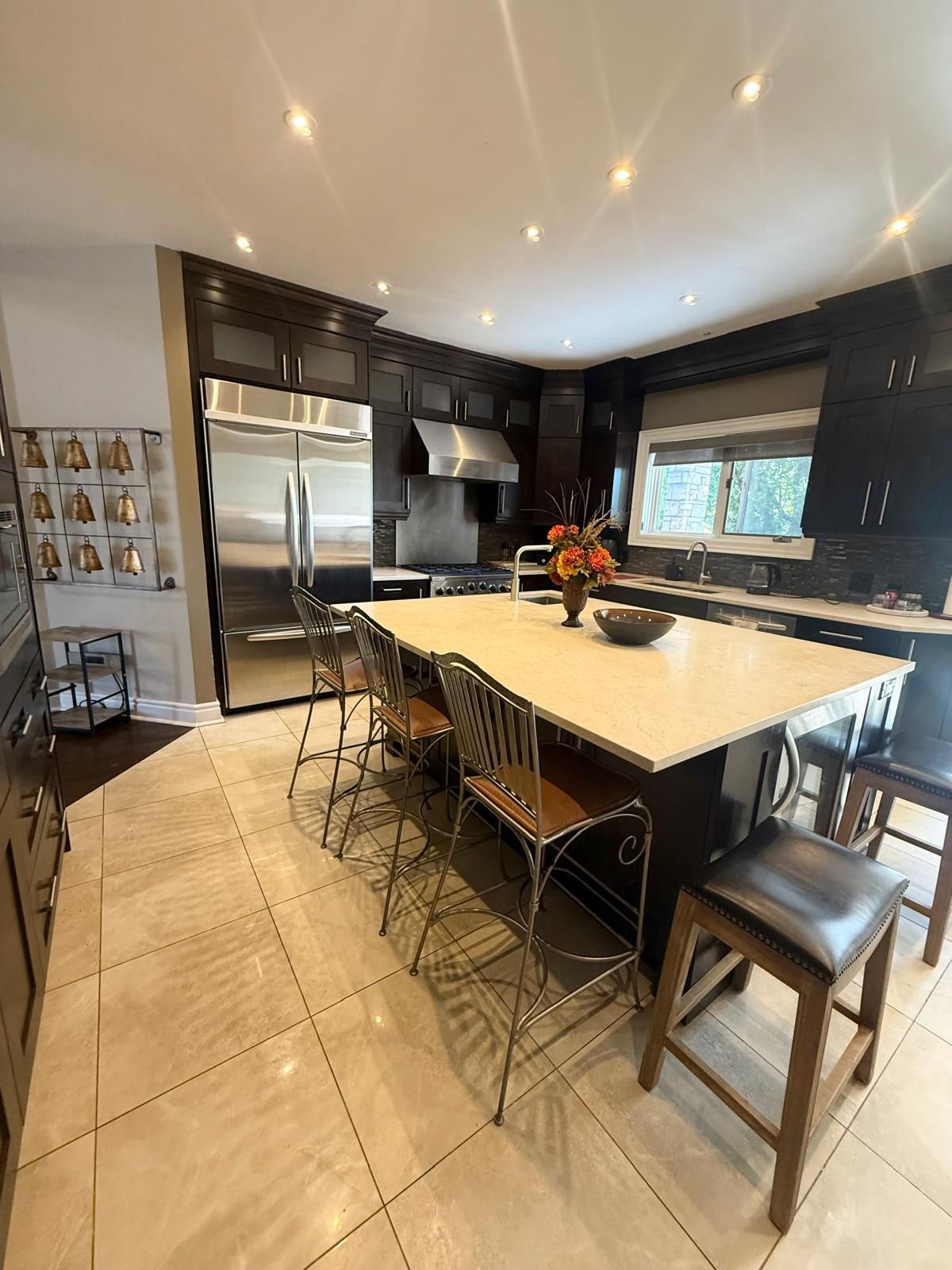A modern kitchen with a central island, stainless steel appliances, and a view to the outside.
