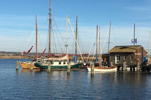Ein Hafen mit mehreren angestaubten Booten, einem Holzgebäude und einem klaren Himmel.