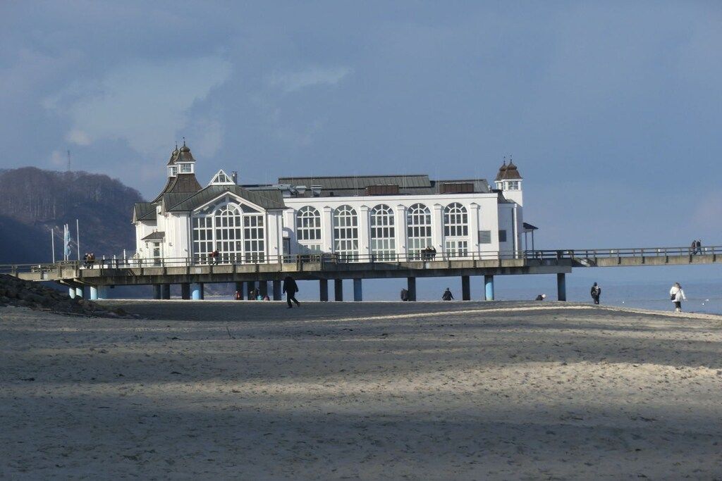 Eine weiße Mole, die ins Wasser führt, mit einem Gebäude am Ende.