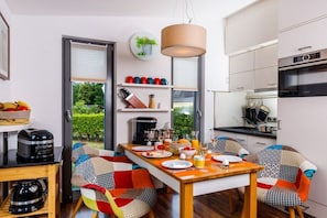 Cozinha moderna com área de jantar, máquina de café e vista para o verde lá fora.
