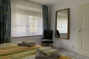 A bedroom with a bed, a chair, a mirror, and a door. - Holiday apartment with 2 bedrooms (Straupitz)