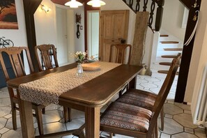 A dining area with a wooden table, chairs, and a woven table runner. - Holiday apartment with 2 bedrooms (Straupitz)