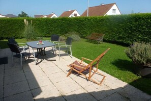 A patio with a table and chairs, a wooden bench, and a well-maintained hedge. - Bredene Fisherman's House (Bredene)