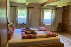 A room with two beds, each with checkered bedding and pillows, a wooden floor, and a window with curtains. - Glacier Chalet by the pond (Flattach)