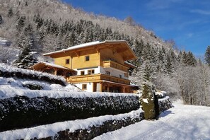 A multi-story wooden chalet with a balcony, set against a snowy mountainous backdrop. - Holiday apartment with 1 bedroom (Kaprun)