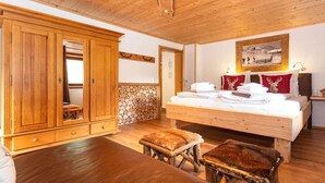 Una habitación con una cama de madera, un armario grande y un banco.
