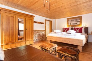 A room with a wooden bed, a large wardrobe, and a bench. - Holiday apartment with 1 bedroom (Kaprun)