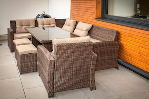 A wicker outdoor seating area with a table and cushioned chairs. - Cabin in Uttendorf with swimming pool (Uttendorf)