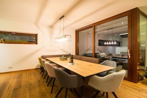 A dining area with a wooden table, grey chairs, and a hanging light fixture. - Cabin in Uttendorf with swimming pool (Uttendorf)