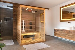 A modern bathroom with a wooden sauna, a large mirror, and a wooden vanity. - Cabin in Uttendorf with swimming pool (Uttendorf)