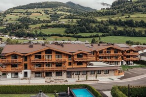 Ein mehrstöckiges Hotel mit Balkonen, einem Swimmingpool und Blick auf die umliegenden Hügel.