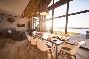 A dining area with a table set for four, chairs, and a view of the sea. - Holiday home in Löbnitz with swimming pool (Löbnitz)