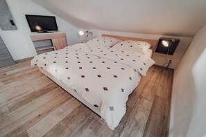 Un dormitorio con cama, televisión y escritorio.